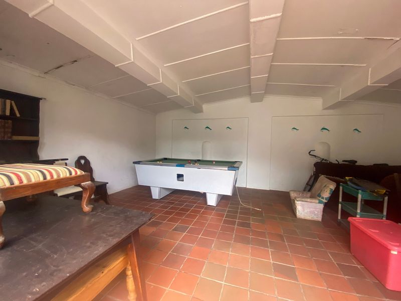 Spacious garage area featuring terracotta tile flooring and an exposed beam ceiling, offering potential for conversion or workshop use.
