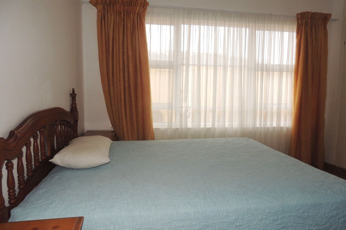 A standard bedroom featuring a large window with installed curtain rails, providing natural light to the space.