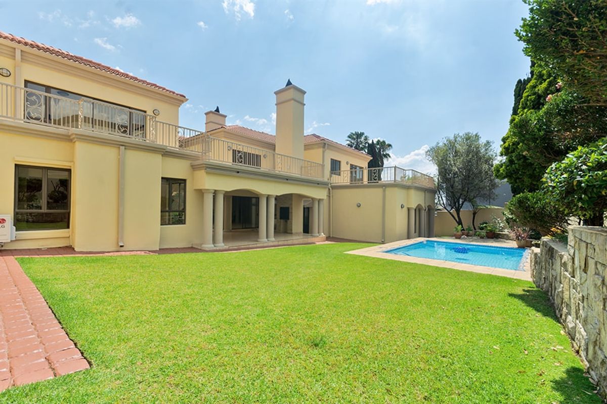 Spacious rear garden featuring a swimming pool, covered patio area, and upper-level balconies with classic architectural detailing.