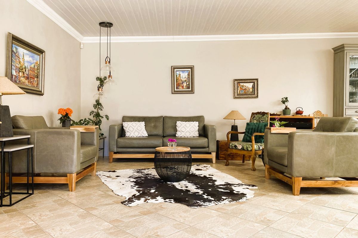 A well-maintained living room featuring neutral tiled flooring, a classic beadboard ceiling with crown molding, and modern pendant lighting.