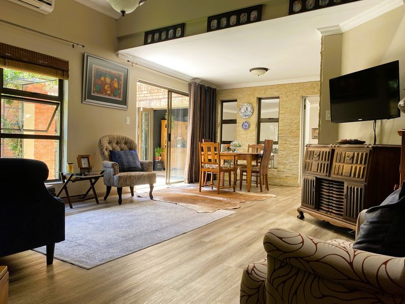 Spacious open-plan living and dining area featuring laminate flooring, a stone accent wall, and large sliding doors providing access to the outdoor patio.