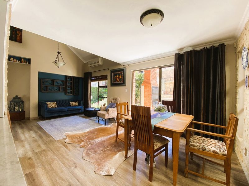 Spacious open-plan living and dining area featuring vaulted ceilings, laminate flooring, and direct access to an outdoor patio through sliding glass doors.