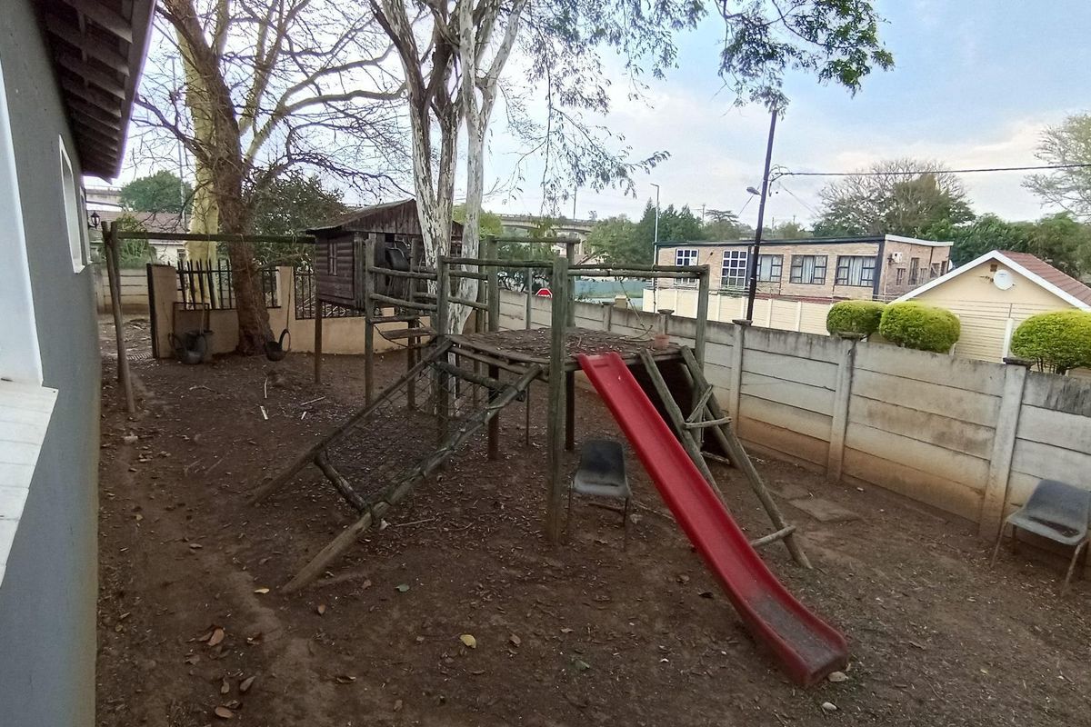 Rear garden area featuring a precast concrete boundary wall and a wooden jungle gym with a slide.