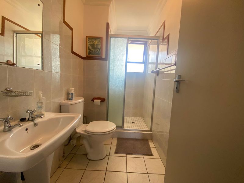 A functional bathroom featuring a pedestal basin, toilet, and a separate shower cubicle with tiled finishes.