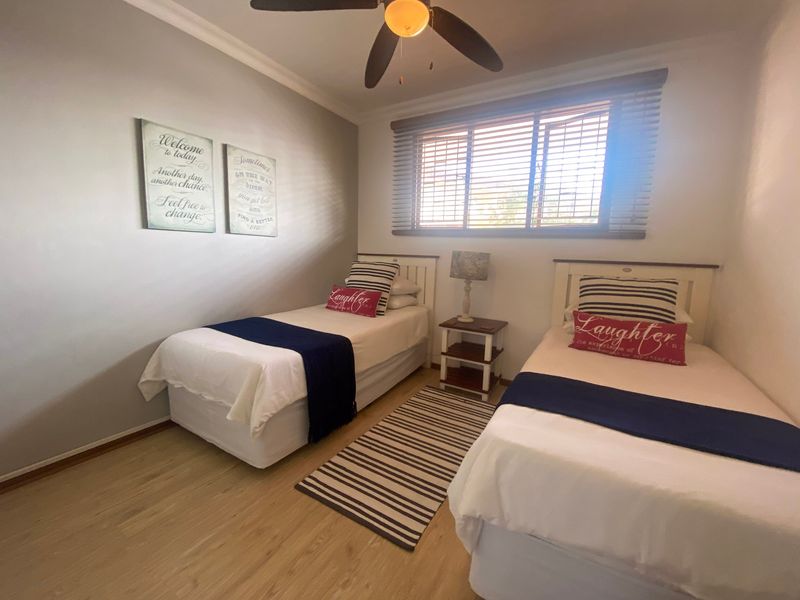 A well-maintained bedroom featuring laminate flooring, a ceiling fan, and venetian blinds, providing a comfortable and functional living space.