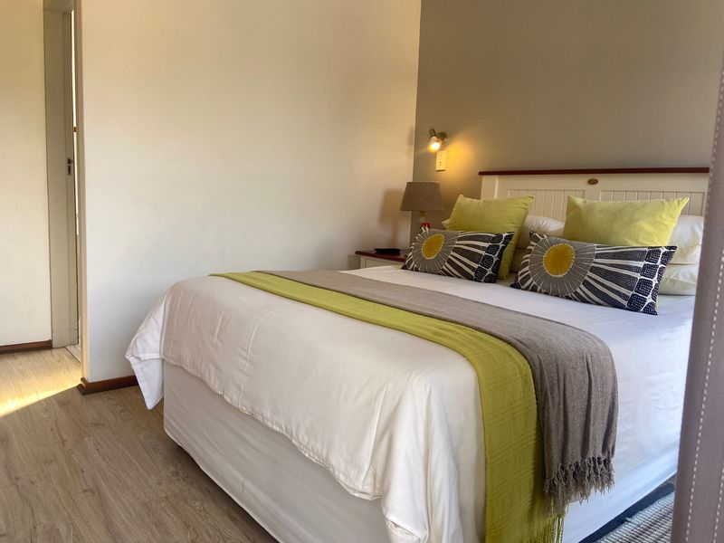 A well-maintained bedroom featuring light-toned laminate flooring and a neutral wall finish, providing a clean and comfortable sleeping space.