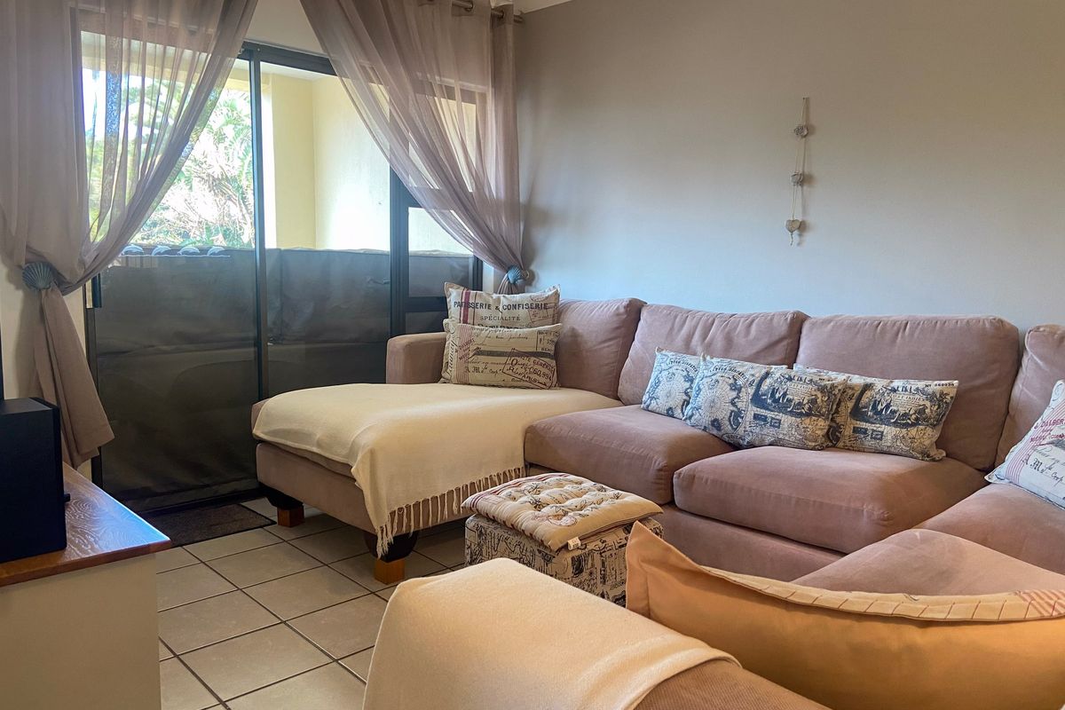 A comfortable living room featuring tiled flooring and a large sliding glass door that provides access to an outdoor patio area.