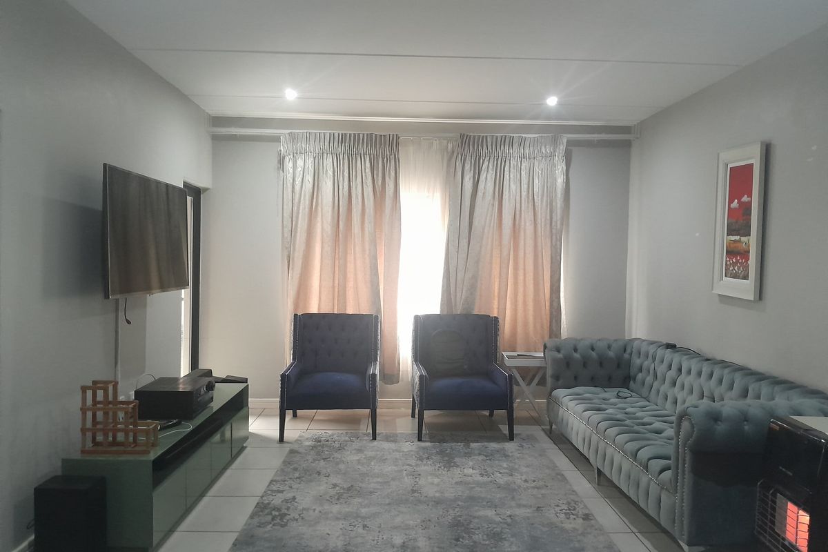 A well-maintained living room featuring neutral wall tones, tiled flooring, and recessed downlighting, creating a comfortable and functional space.