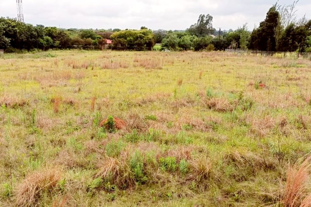 A large, open, undeveloped plot of land featuring natural grass and perimeter fencing, suitable for agricultural or residential development.