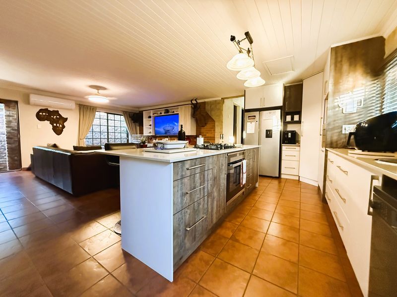 Spacious open-plan living area featuring a modern kitchen with a central island, built-in appliances, and tiled flooring throughout.