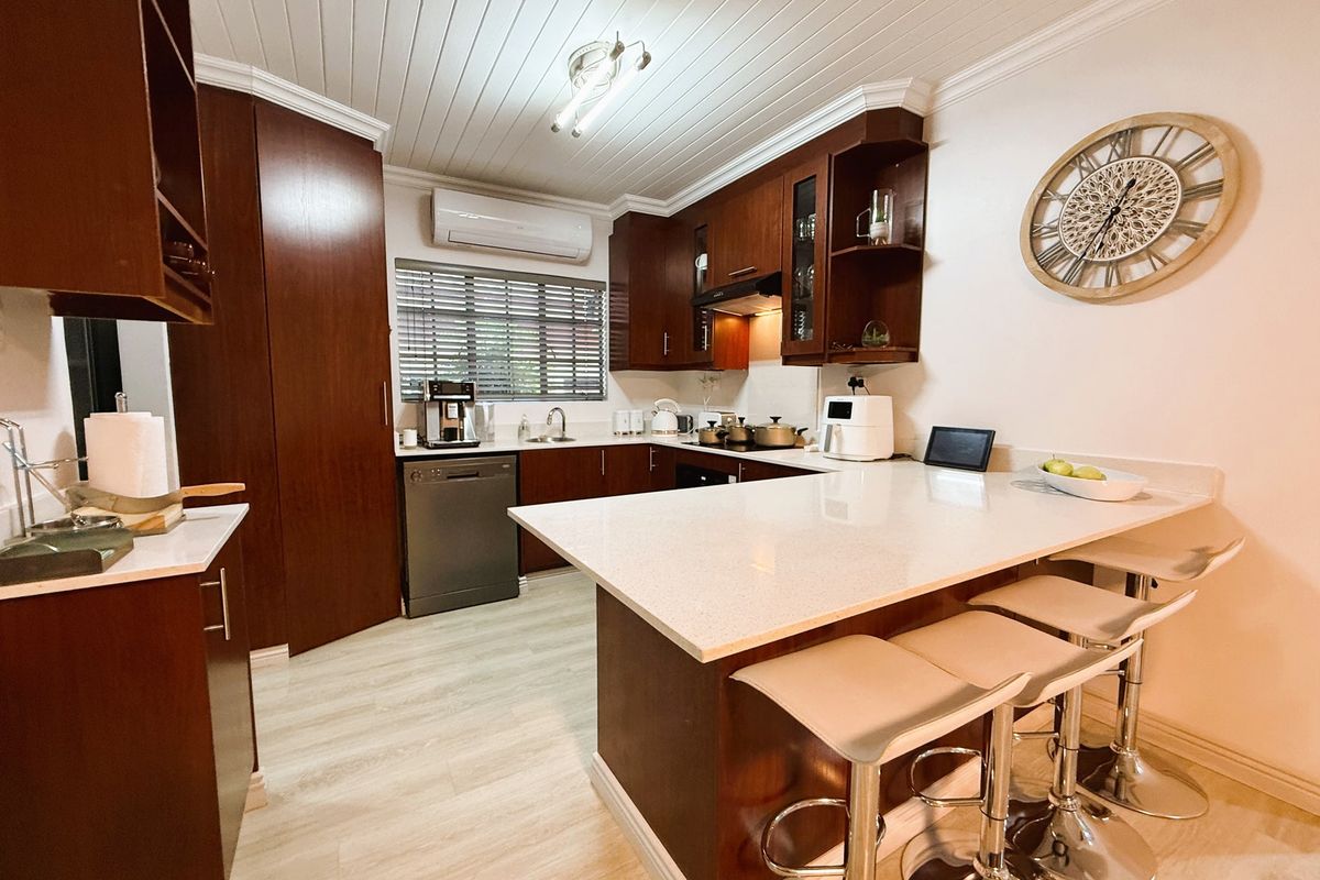A well-maintained kitchen featuring dark wood cabinetry, stone countertops, a breakfast bar, and a split-system air conditioner, finished with a tongue and groove ceiling.