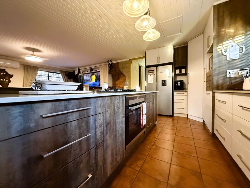 Open plan kitchen featuring a central island with built-in oven and hob, complemented by modern cabinetry and tiled flooring.