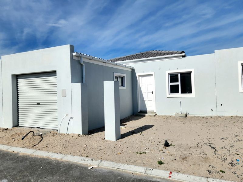 Front elevation of a modern single-story house featuring a roller garage door, white panel entrance door, and aluminium window frames with unfinished landscaping.