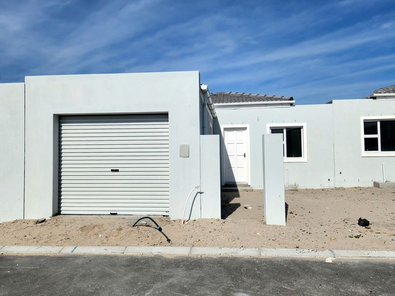 Front elevation of a modern single-story house featuring a roller garage door, white exterior walls, and an unfinished garden area.