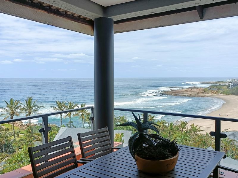 Spacious covered balcony featuring a glass balustrade and panoramic ocean views, providing an ideal outdoor space for relaxation and coastal living.