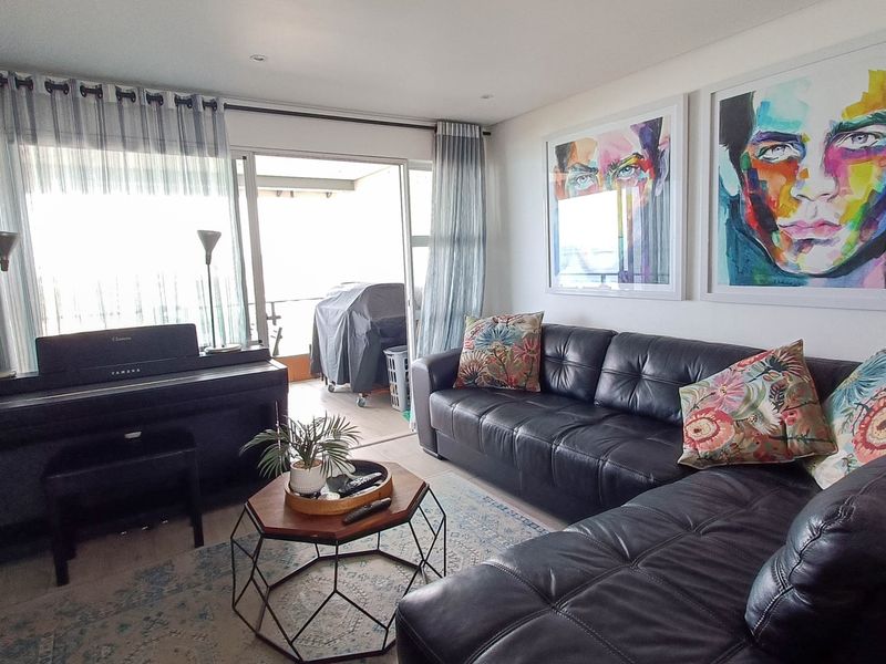 A well-lit living room featuring a large sliding glass door that provides access to an outdoor balcony area.