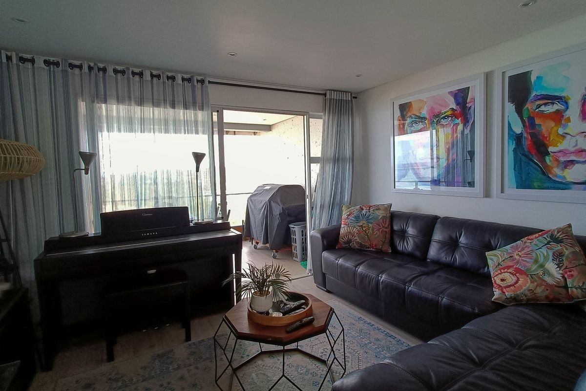 A comfortable living room featuring recessed lighting and large sliding glass doors that provide access to an outdoor balcony area.