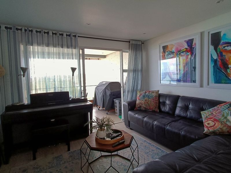 A comfortable living room featuring recessed lighting and large sliding glass doors that provide access to an outdoor balcony area.