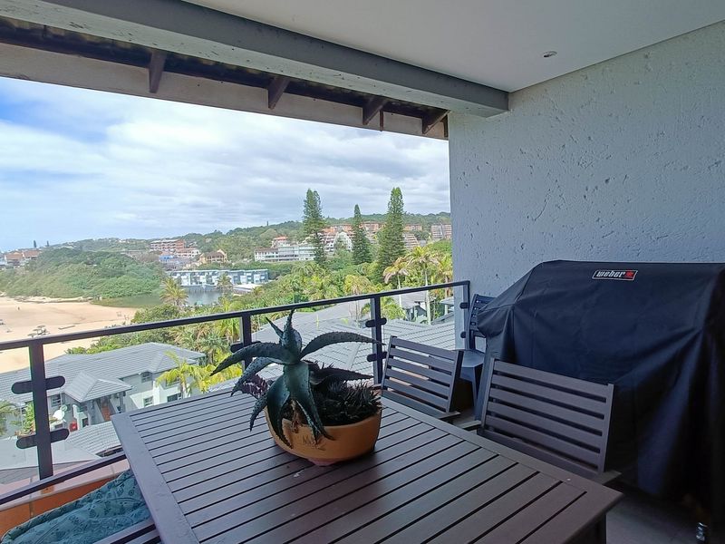 A covered balcony featuring a metal balustrade and tiled flooring, offering expansive coastal and landscape views.