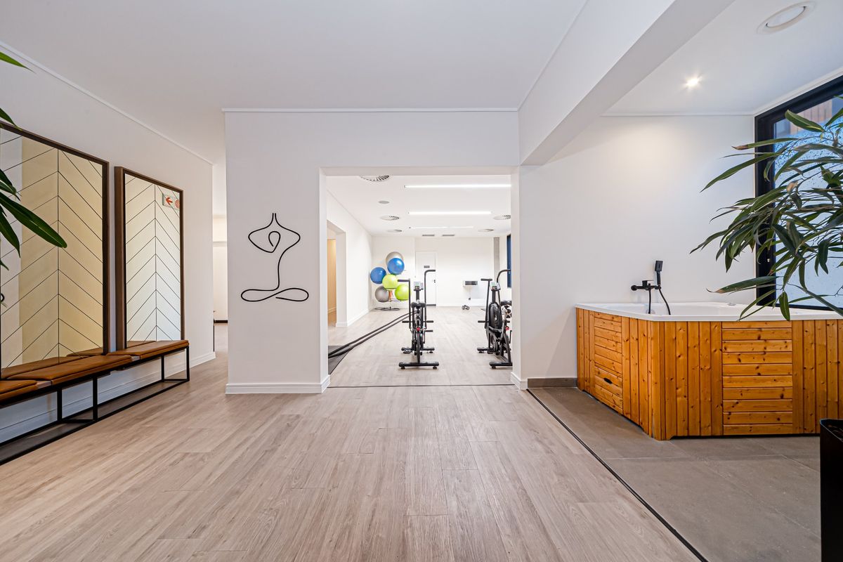 Modern gym facility featuring wood-look flooring, recessed lighting, and a built-in sauna unit with integrated shower fixtures.