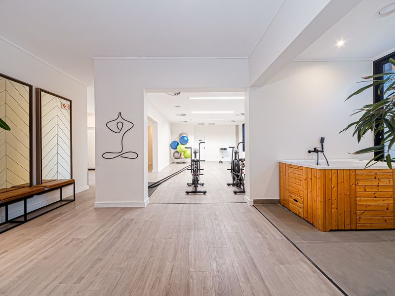 Modern gym facility featuring wood-look flooring, recessed lighting, and a built-in sauna unit with integrated shower fixtures.