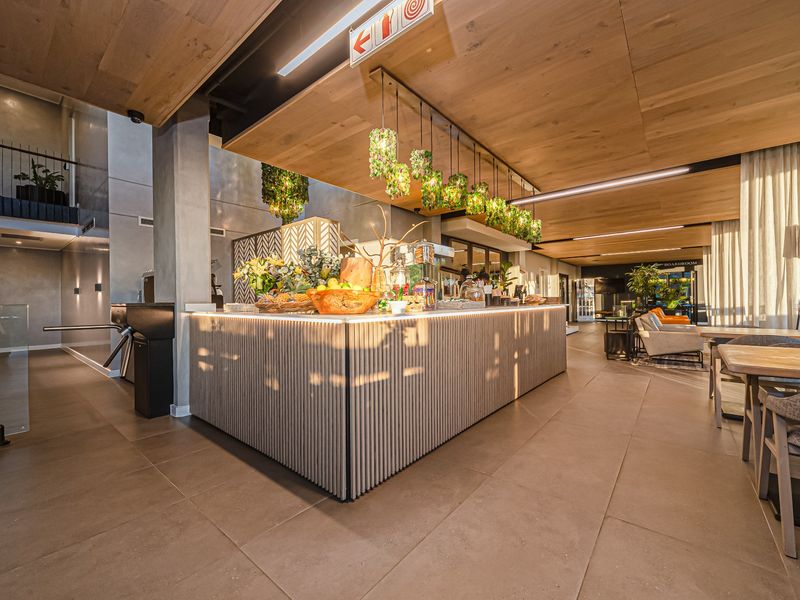 Modern clubhouse area featuring a stylish built-in bar counter, timber ceiling accents, and high-quality tiled flooring in a contemporary open-plan setting.