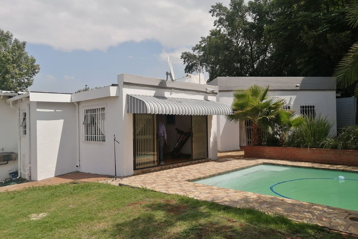 Rear view of the property featuring a swimming pool, paved patio area, and direct access to the interior living space via sliding doors.