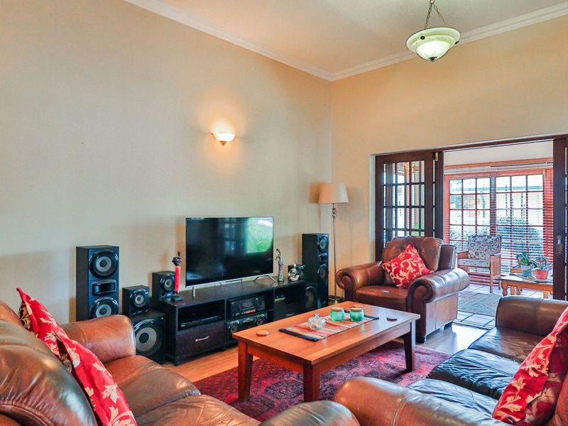 Spacious living room featuring vaulted ceilings, hardwood flooring, and timber-framed glass sliding doors that provide seamless access to the outdoor patio area.