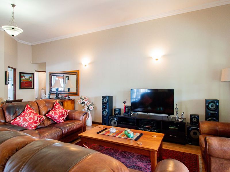 A comfortable living room featuring hardwood flooring, decorative cove cornicing, and warm wall sconce lighting, creating a welcoming and functional space.