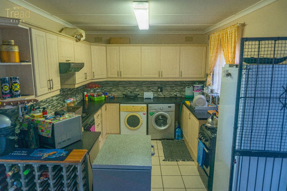 Functional kitchen featuring ample built-in cabinetry, tiled backsplash, and integrated laundry facilities, offering a practical layout with potential for modern cosmetic updates.
