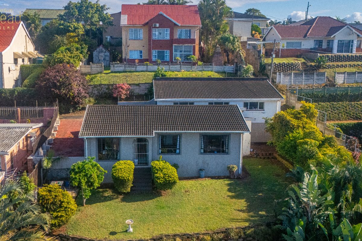 Aerial view of a residential property featuring a tiled roof, front garden, and established landscaping in a suburban neighborhood setting.