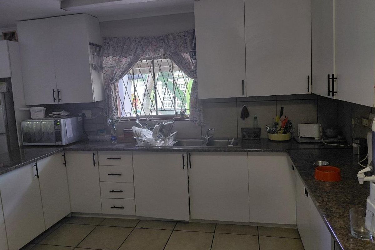 Functional kitchen featuring white cabinetry, laminate countertops, double bowl sink, and tiled flooring, offering a practical layout for daily meal preparation.