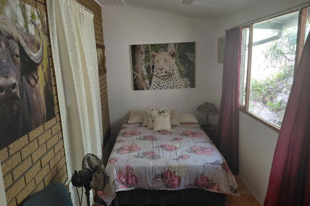 A bedroom featuring exposed brick walls, tiled flooring, and a large window providing natural light.