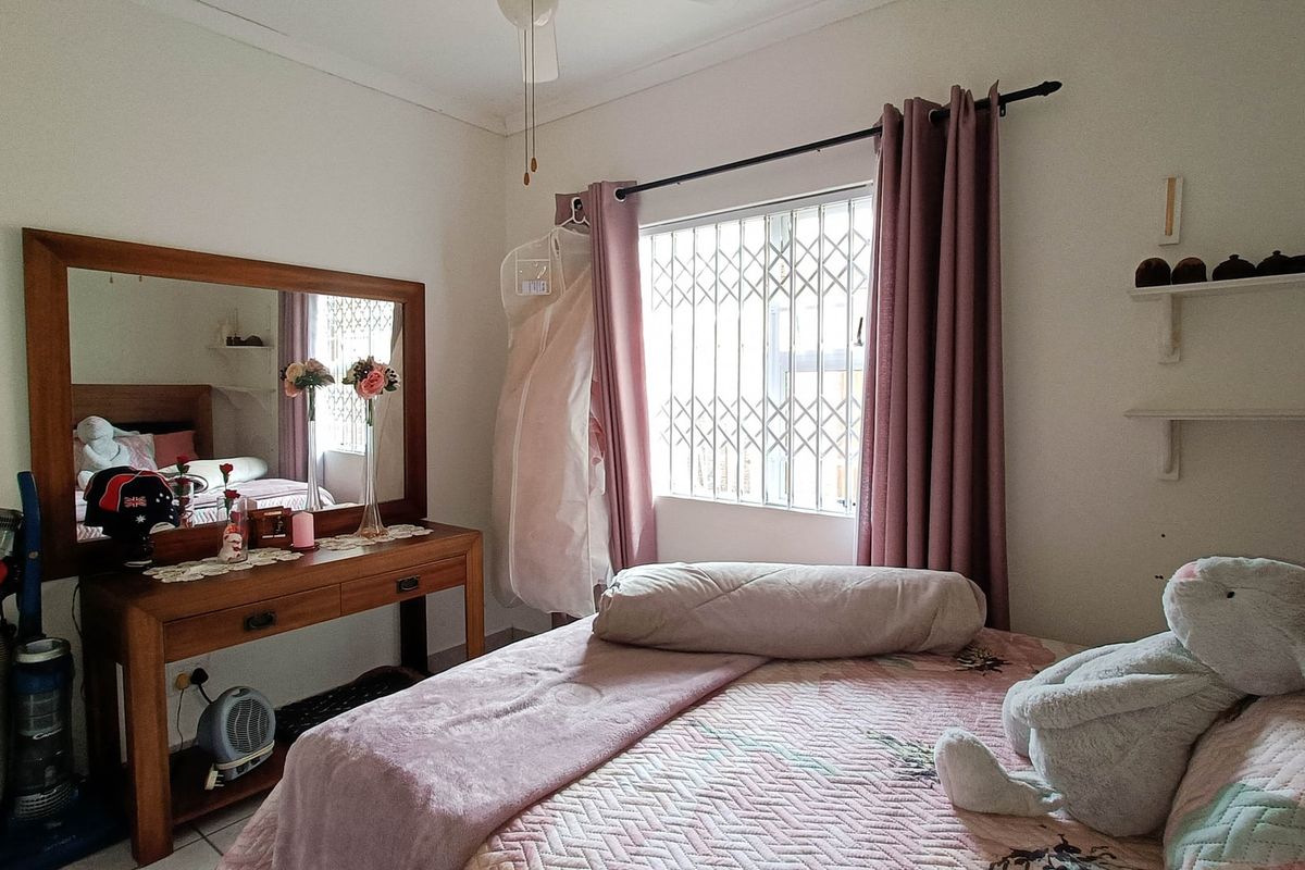 A bedroom featuring a security gate on the window, a ceiling fan, and built-in wall shelving.