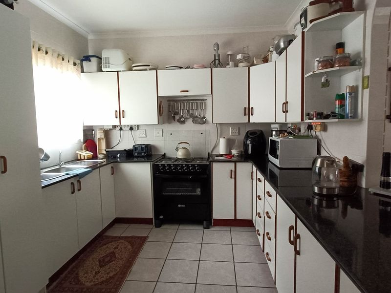 A functional kitchen featuring white cabinetry, dark granite countertops, a gas stove with oven, and tiled flooring.