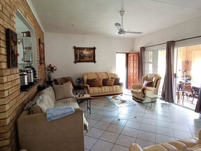 Spacious living room featuring exposed brick accent wall, tiled flooring, and large sliding glass doors providing access to the patio area.