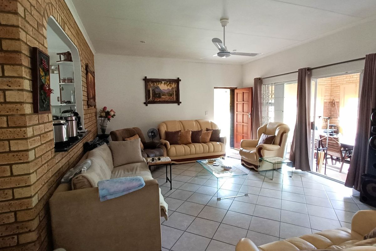 Spacious living room featuring exposed brick accent wall, tiled flooring, and large sliding glass doors providing access to the patio area.