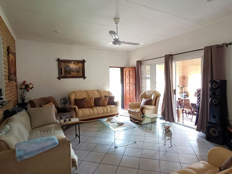Spacious living room featuring tiled flooring, an exposed brick feature wall, and sliding glass doors providing direct access to the patio area.