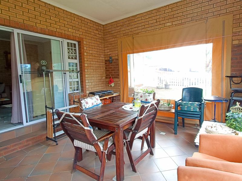 A covered patio area featuring exposed brick walls, tiled flooring, and roll-up canvas blinds, providing a functional outdoor living space.
