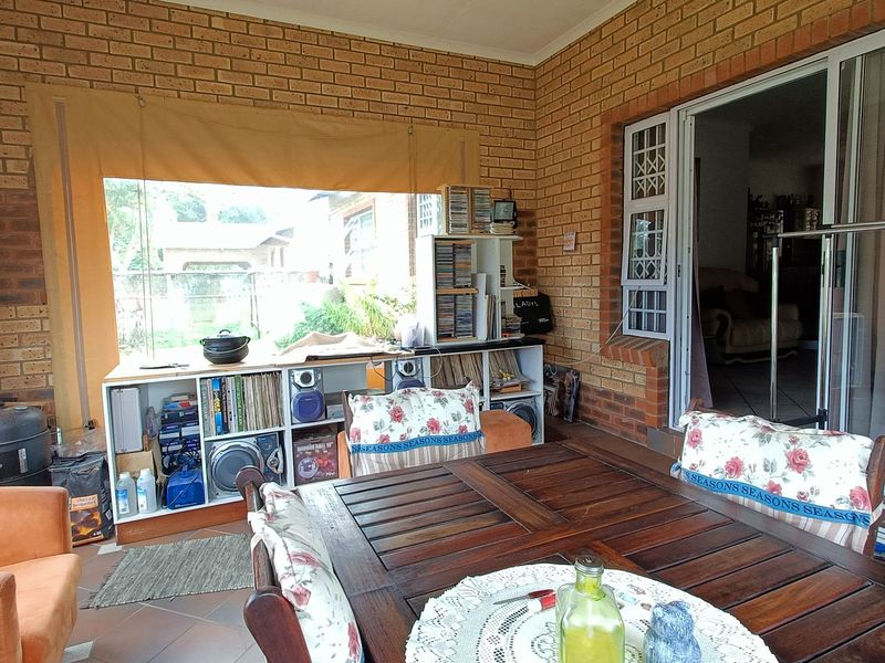 A covered patio area featuring exposed brick walls, tiled flooring, and sliding glass door access to the main living space.