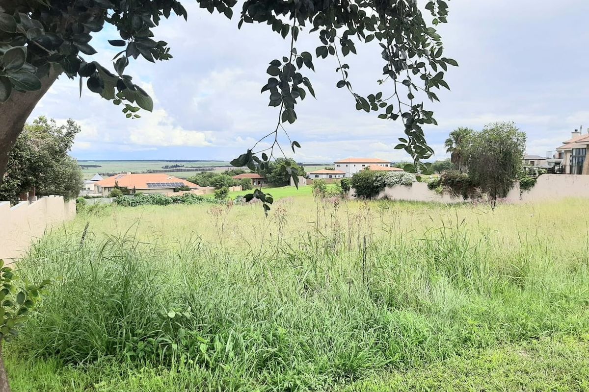 A view overlooking a vacant residential plot with surrounding neighborhood houses and distant landscape scenery.
