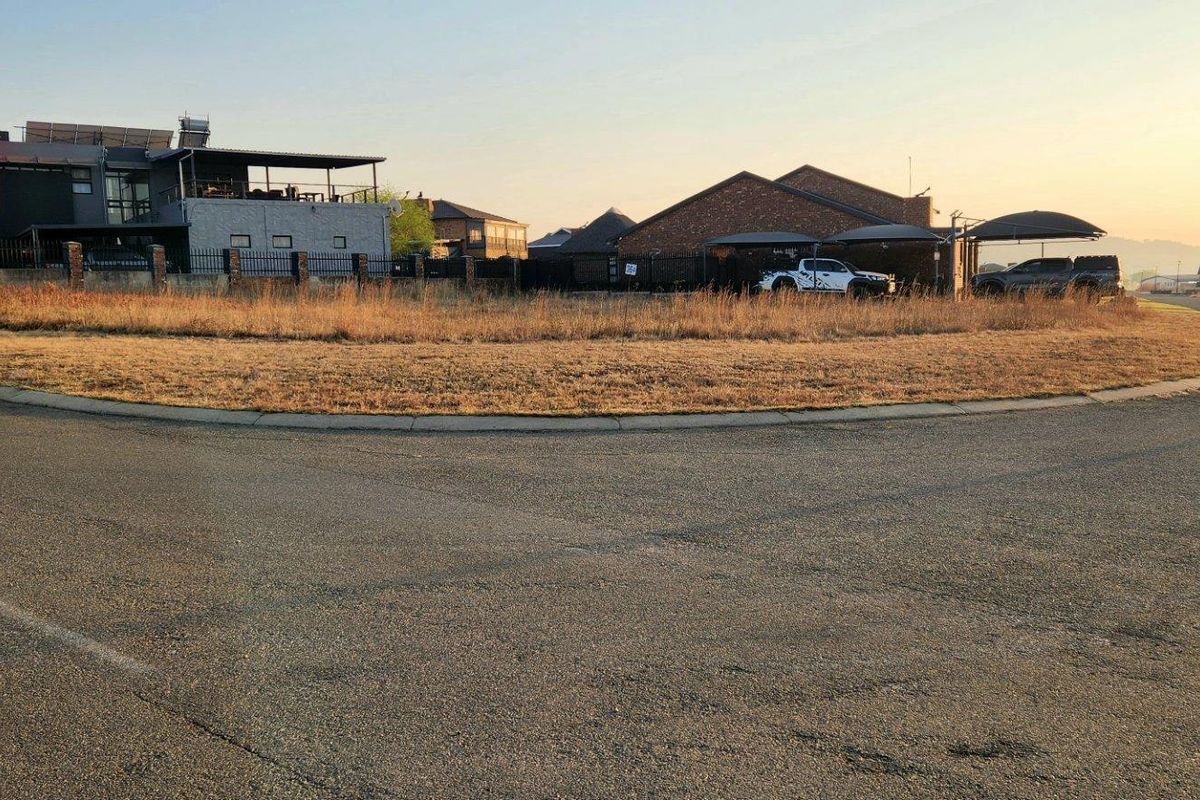A street-level view of a vacant residential plot situated on a corner lot within a developed neighborhood.