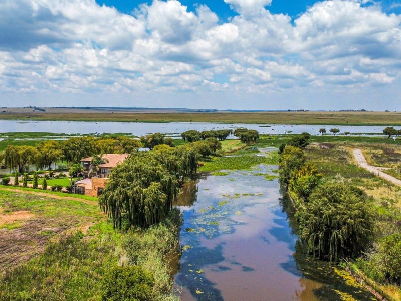 An aerial view of the residential property showcasing the expansive natural landscape, waterway, and surrounding wetland environment.