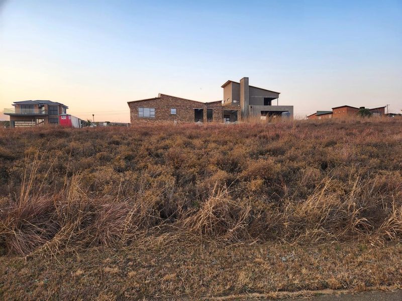 A view of a vacant residential plot featuring an unfinished building structure under construction in a developing estate.