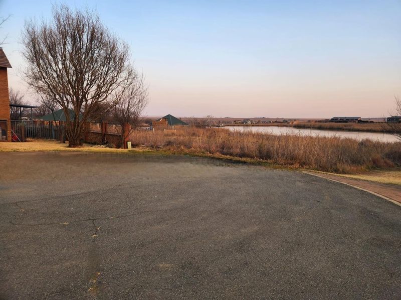 A view of the vacant residential land featuring an asphalt driveway, brick boundary wall, and scenic waterfront outlook.