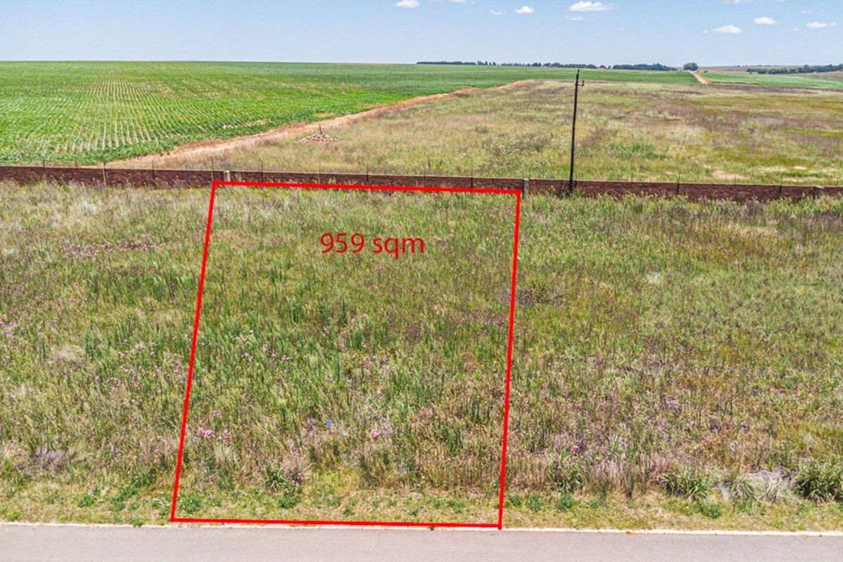 An aerial view of a 959 sqm vacant residential plot, featuring open land with boundary fencing and access to local utility infrastructure.