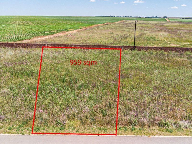 An aerial view of a 959 sqm vacant residential plot, featuring open land with boundary fencing and access to local utility infrastructure.