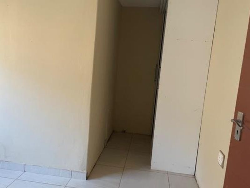 A small hallway area featuring tiled flooring and a built-in cupboard, providing functional storage space within the apartment.