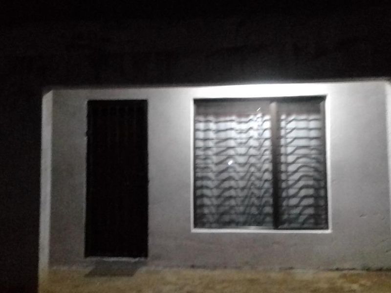 Night view of the property exterior featuring a secure entrance door and window with protective security bars.