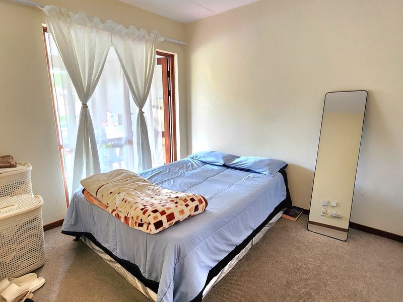 A functional bedroom featuring carpet flooring, a built-in wardrobe, and a sliding glass door providing access to the exterior.